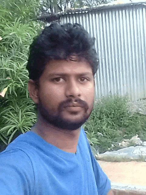 a man with a beard wearing a blue shirt takes a selfie
