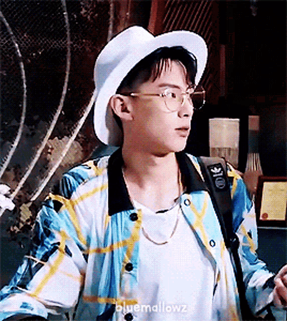 a young man wearing a hat and glasses has the word bluemallowz on the bottom of his shirt