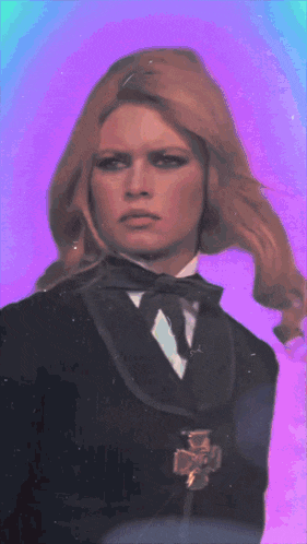 a woman in a tuxedo with a medal around her neck looks at the camera