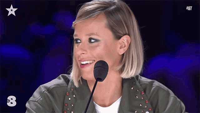 a woman speaking into a microphone with the number 8 on the bottom left