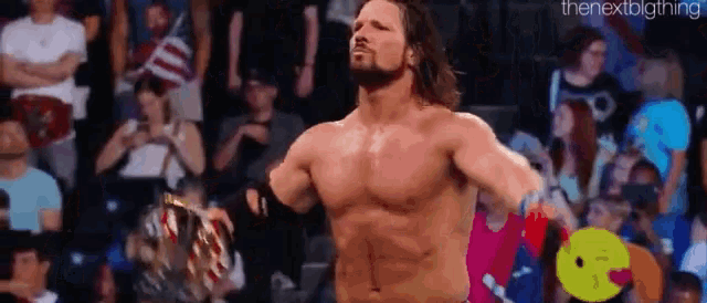 a shirtless wrestler is standing in front of a crowd holding a championship belt .