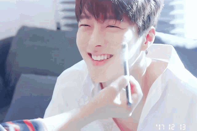a person is applying makeup to a young man 's face and smiling