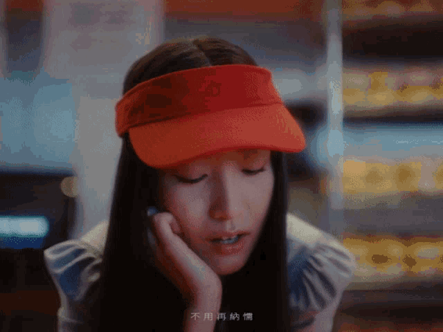 a woman wearing a red hat and visor has chinese writing on her face