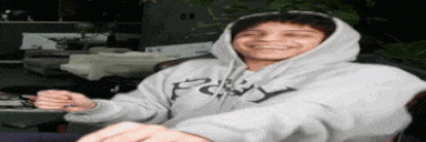 a man wearing a hoodie is sitting in a chair .