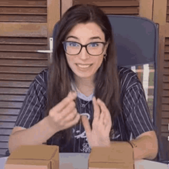 a woman wearing glasses and a striped shirt is sitting at a table .