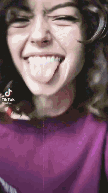 a woman in a purple shirt is sticking her tongue out ..