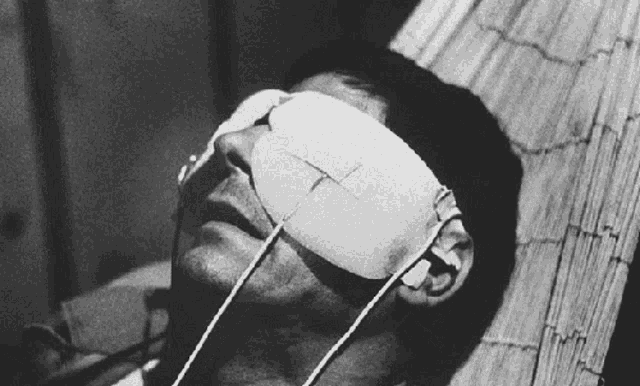 a man with a bandage on his eye is laying on a bed