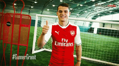 a man wearing a red fly emirates jersey giving a thumbs up
