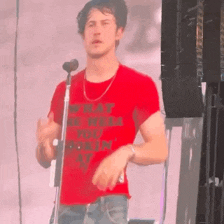 a man in a red shirt is singing into a microphone