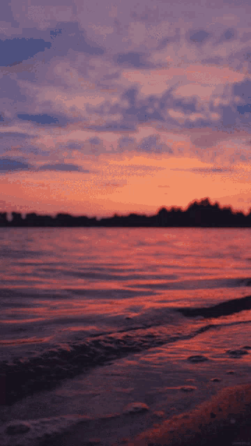 a sunset over a body of water with a pink sky