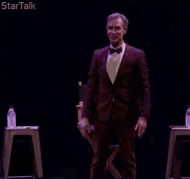 a man in a purple suit and bow tie is giving a thumbs up and saying " yes "