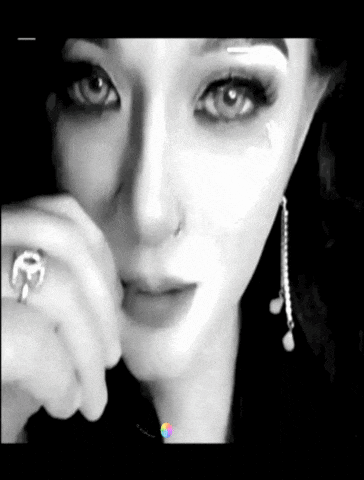 a black and white photo of a woman wearing a nose ring and earrings