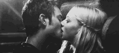 a man and a woman are kissing in front of a wall in a black and white photo .