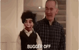 a man in a plaid shirt is standing next to a scary puppet .