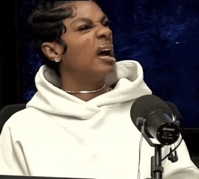 a woman is sitting in front of a microphone with her mouth open .