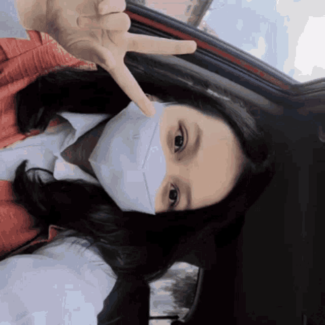 a girl wearing a mask is giving the peace sign