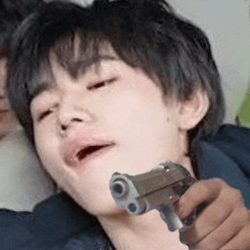 a young boy is holding a gun to his face .