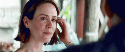 a close up of a woman touching her hair while looking at a man .