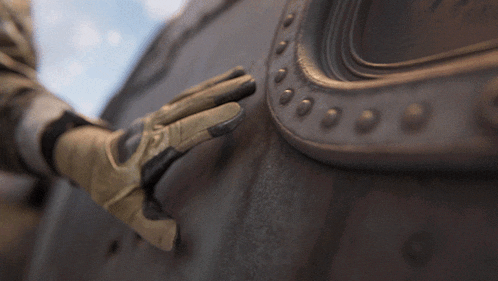 a person wearing a pair of gloves is touching a piece of metal