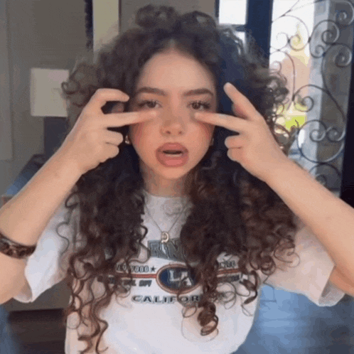 a woman with curly hair is wearing a white shirt that says california