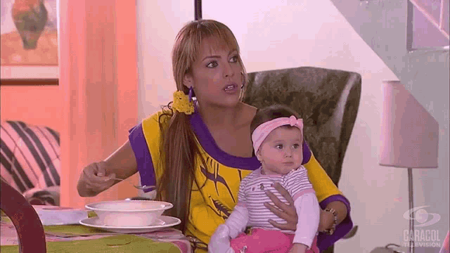 a woman is holding a baby in her arms and the word caracol is on the bottom of the image