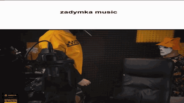 a man in a yellow shirt is standing in front of a microphone and the words zadymka music are above him