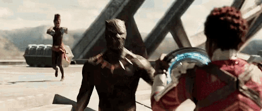 a black panther is standing next to a man in a red jacket .