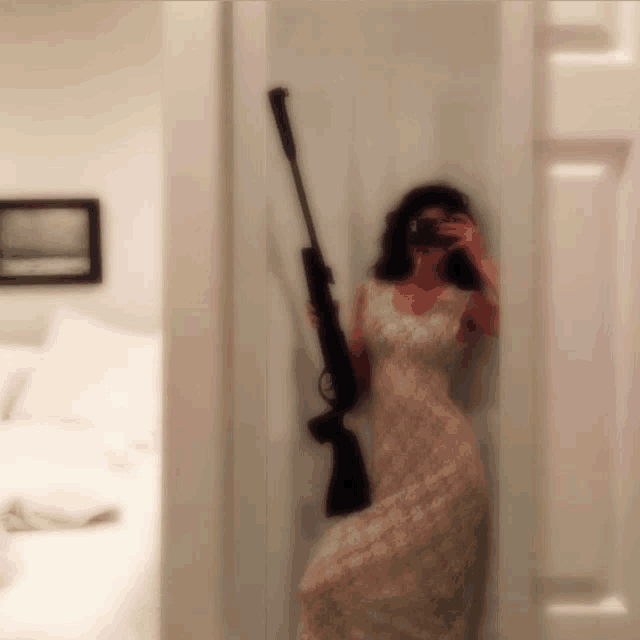 a woman in a white dress is holding a rifle