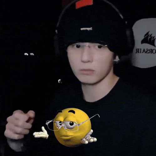 a man wearing a black hat and headphones holds a yellow smiley face