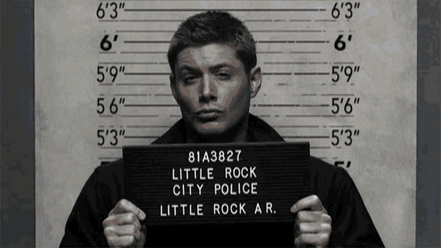 a man holds up a little rock city police sign