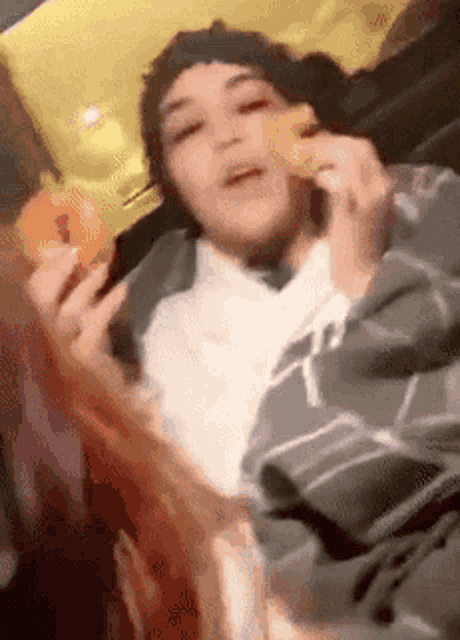 a person laying on a bed eating a donut and a slice of pizza