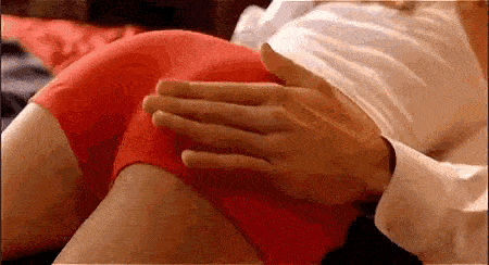 a man is putting his hands on a woman 's butt while she is wearing red shorts .