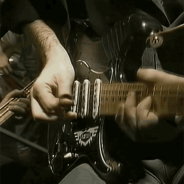 a man is playing a guitar with the letter f on the neck