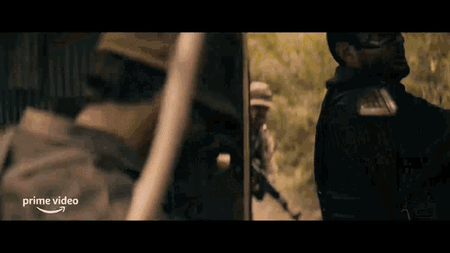a group of soldiers are standing next to each other in a field with a sign that says prime video .