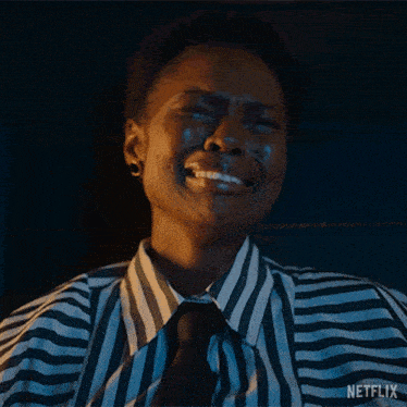 a woman wearing a striped shirt and tie is crying with tears running down her face .