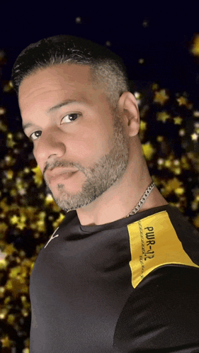 a man with a beard wears a black shirt with a yellow patch that says pwr-112