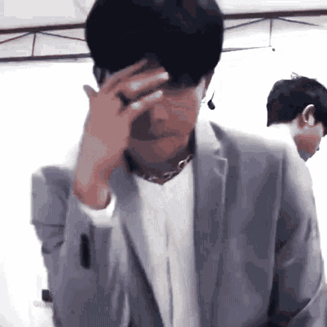 a man in a suit is covering his face with his hand