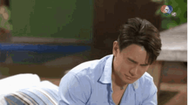 a man in a blue shirt is laying on a couch with his head down .