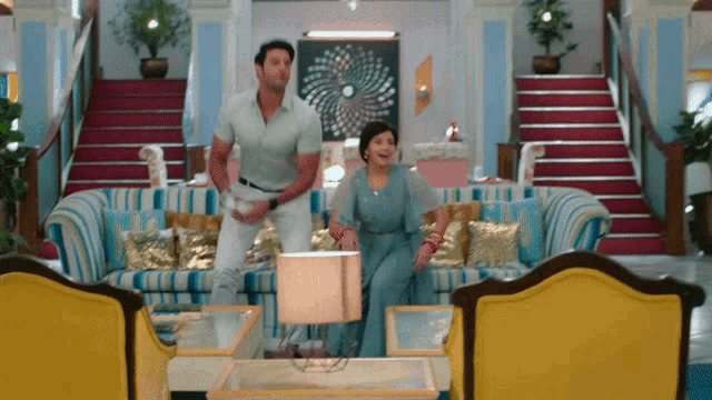 a man and a woman are dancing in a living room with stairs in the background