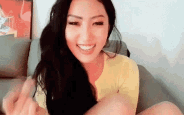 a woman is sitting on a couch with her legs crossed and smiling .
