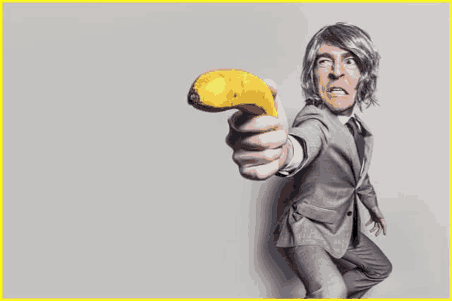 a man in a suit and tie is pointing a banana at the camera