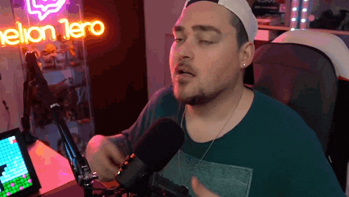 a man singing into a microphone in front of a neon sign that says " helion 1ero "