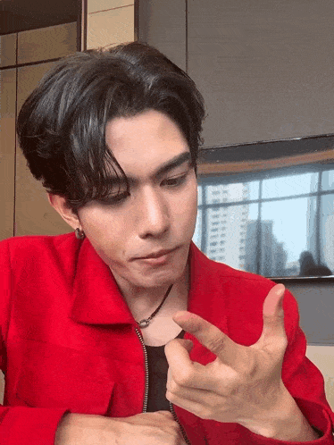 a young man wearing a red jacket is making a funny face