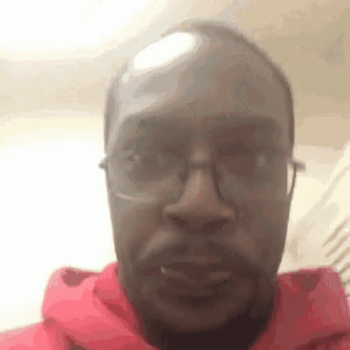 the man is wearing glasses and a red hoodie