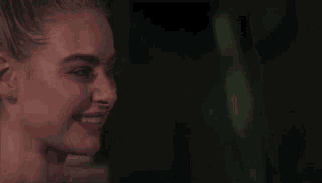 a close up of a woman 's face smiling in a dark room