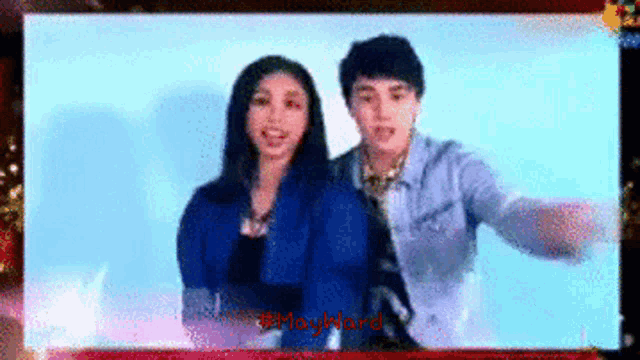 a man and a woman are standing next to each other in front of a screen that says mayward on it