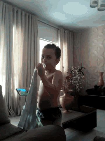a shirtless boy is standing in front of a window