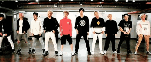 a group of young men are standing in a line on a dance floor