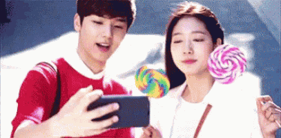 a man is taking a picture of a woman with a lollipop while she holds a lollipop .