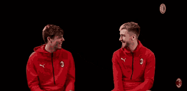 two men in red puma sweatshirts are laughing